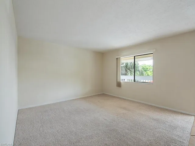 Empty room featuring a textured ceiling and light colored carpet