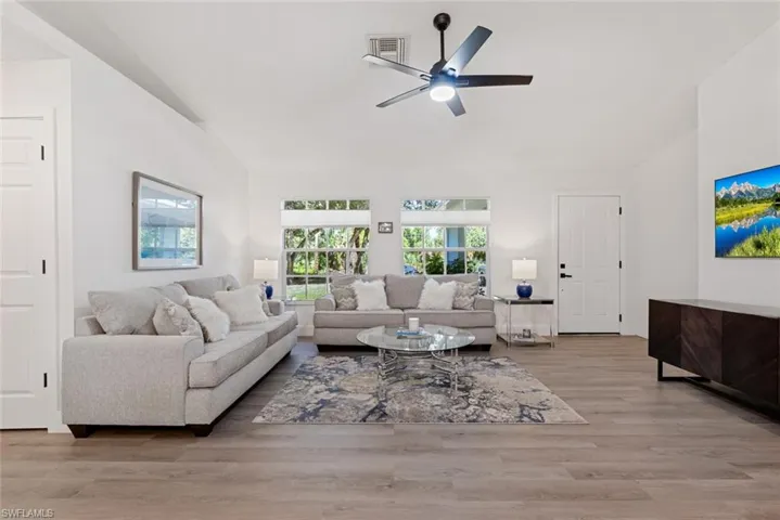 Living room featuring wood-type flooring, vaulted ceiling, and ceiling fan