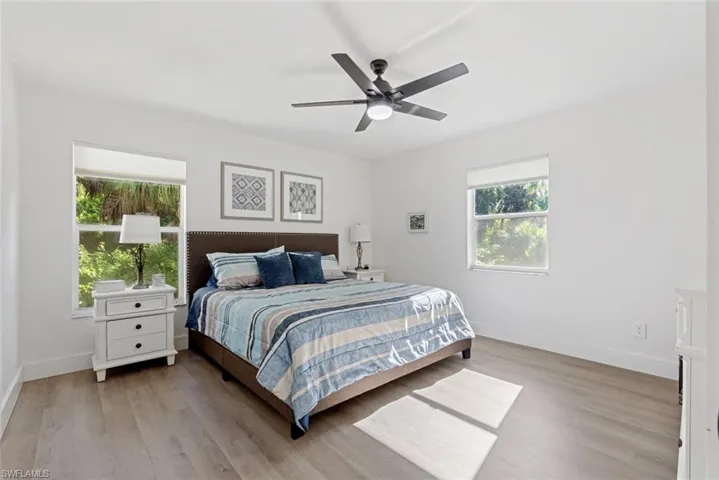 Bedroom with light hardwood / wood-style floors, multiple windows, and ceiling fan