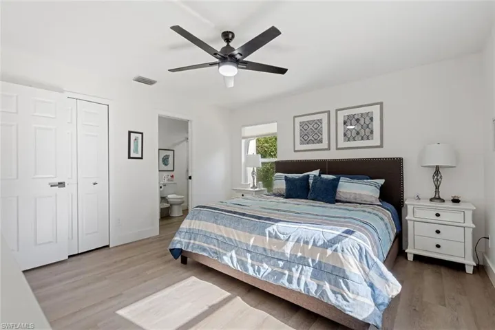 Bedroom with a closet, ensuite bathroom, wood-type flooring, and ceiling fan