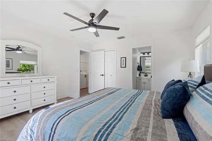 Bedroom featuring wood-type flooring, connected bathroom, multiple windows, and ceiling fan