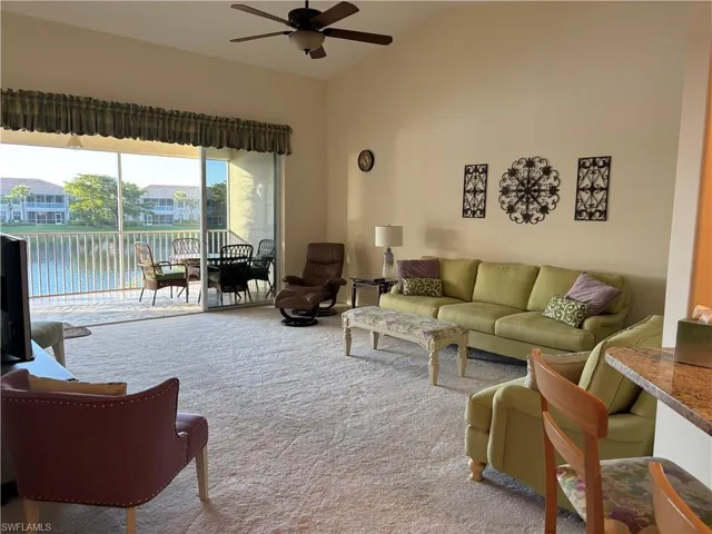 Carpeted living room with a water view, ceiling fan, and lofted ceiling