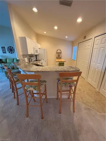 Kitchen featuring kitchen peninsula, tasteful backsplash, white cabinets, range, and fridge