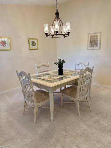 Carpeted dining area with an inviting chandelier