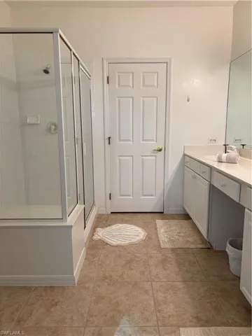 Bathroom with tile patterned floors, vanity, and an enclosed shower