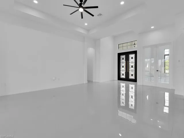 Tiled entryway featuring ceiling fan, french doors, and a tray ceiling