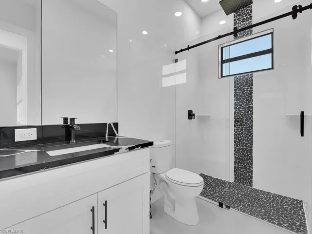 Bathroom with an enclosed shower, vanity, and toilet