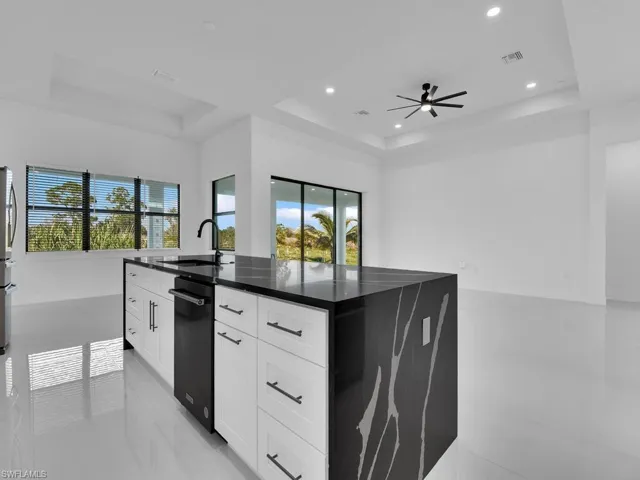 Kitchen featuring white cabinetry, a raised ceiling, and sink