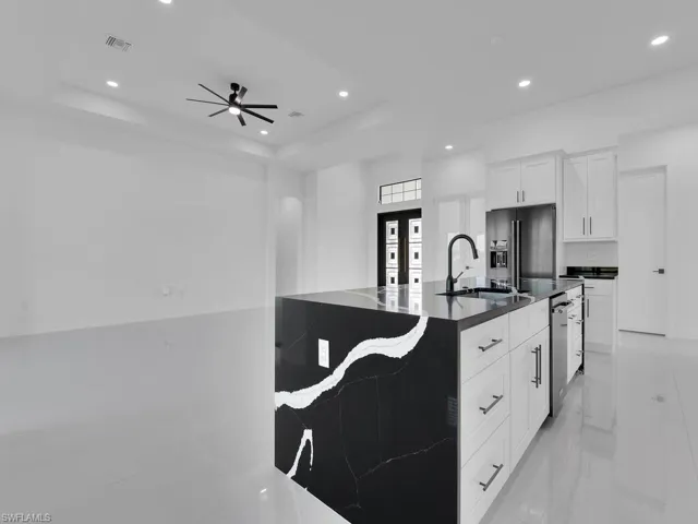Kitchen featuring stainless steel dishwasher, high quality fridge, a tray ceiling, and white cabinetry
