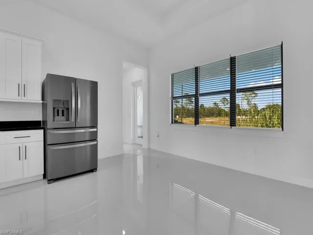 Kitchen with stainless steel fridge, plenty of natural light, and white cabinetry