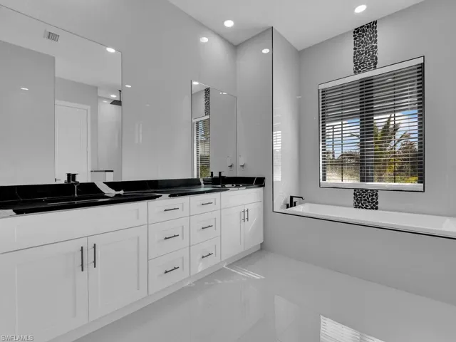 Bathroom featuring vanity, a bathing tub, and tile patterned flooring