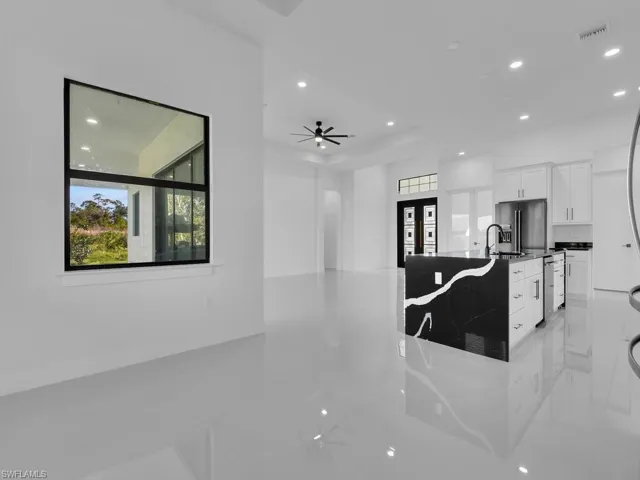 Kitchen with ceiling fan, white cabinetry, dark stone countertops, and dishwasher
