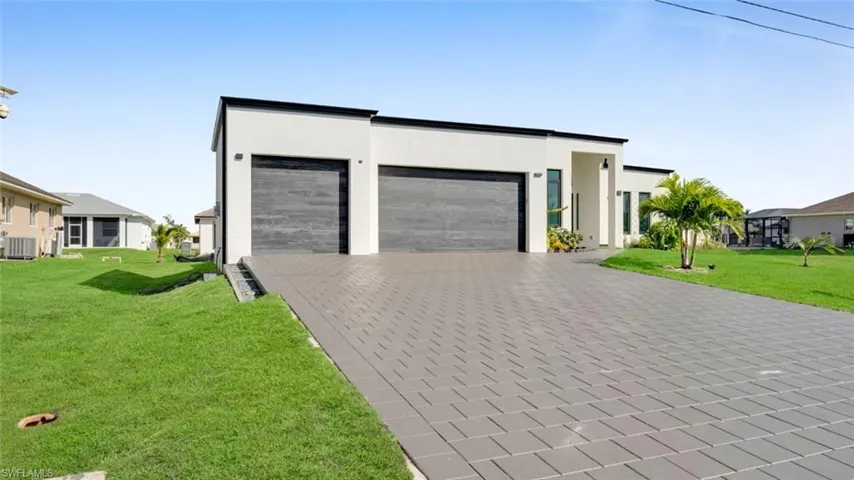 Modern home with a front yard, decorative driveway, an attached garage, and stucco siding