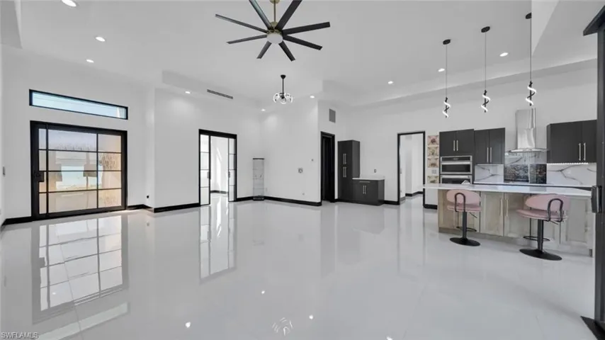 Kitchen featuring open floor plan, a kitchen bar, decorative light fixtures, a high ceiling, and dark cabinets
