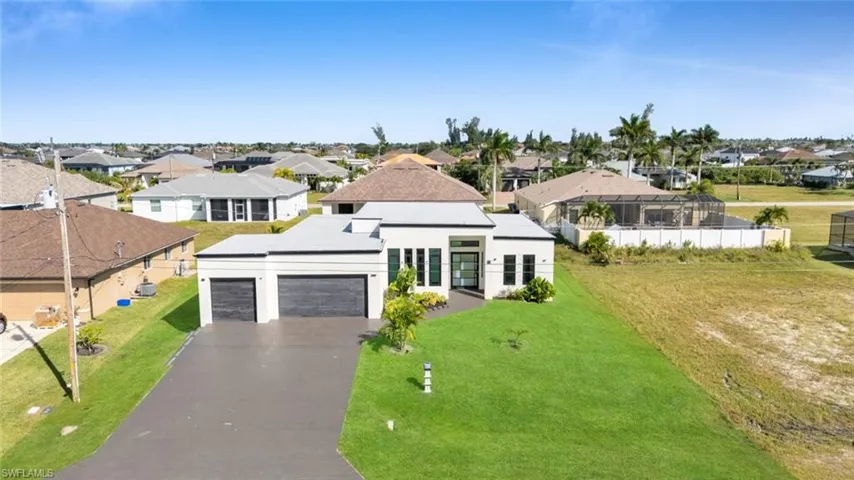 View of front facade featuring a garage, driveway, a residential view, stucco siding, and a front lawn