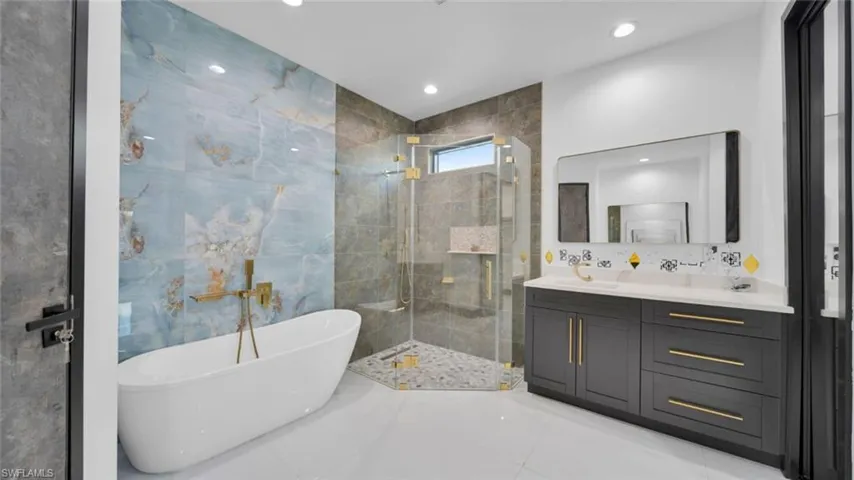 Full bath featuring vanity, a shower stall, a freestanding tub, recessed lighting, and light tile patterned floors