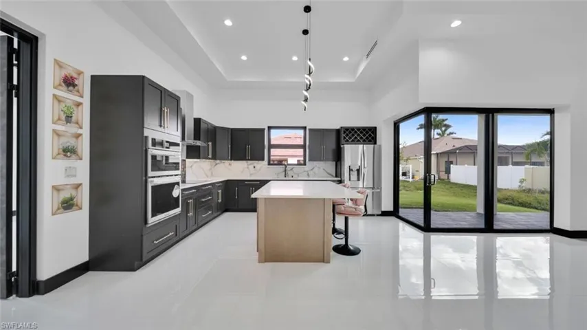 Kitchen featuring a kitchen island, stainless steel appliances, a breakfast bar, decorative backsplash, and light stone countertops