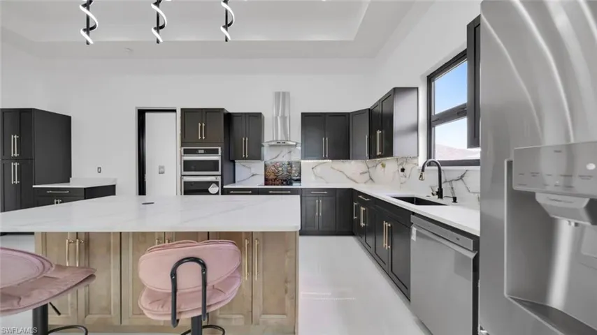 Kitchen featuring stainless steel appliances, light stone countertops, a center island, decorative backsplash, and a breakfast bar area