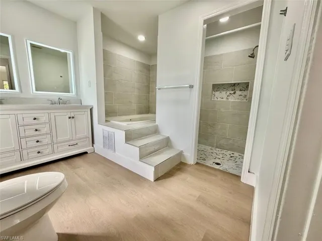 Bathroom featuring vanity, plus walk in shower, and hardwood / wood-style flooring