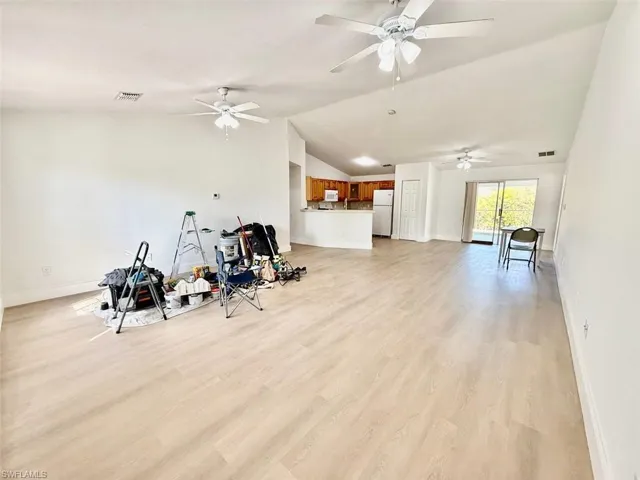 Workout room with ceiling fan, lofted ceiling, and light hardwood / wood-style flooring