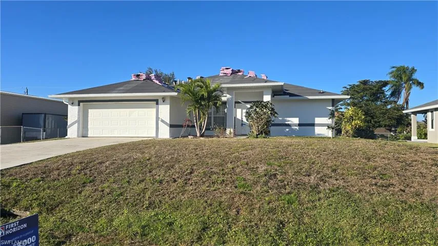 View of front facade featuring a garage and a front lawn