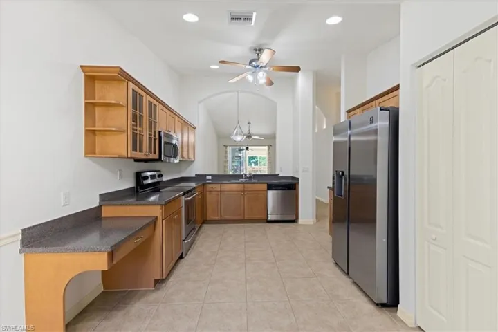 Kitchen featuring ceiling fan, lofted ceiling, light tile patterned floors, sink, and appliances with stainless steel finishes
