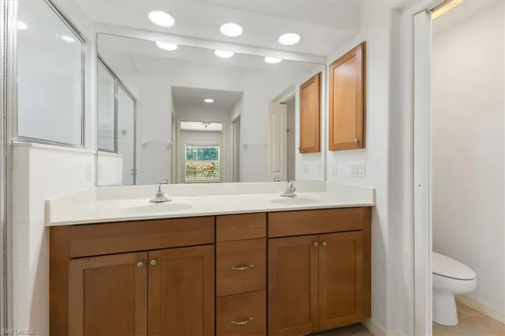 Bathroom with vanity, tile patterned flooring, toilet, and a shower with door