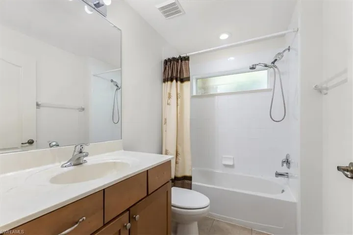 Full bathroom with shower / tub combo with curtain, tile patterned flooring, vanity, and toilet