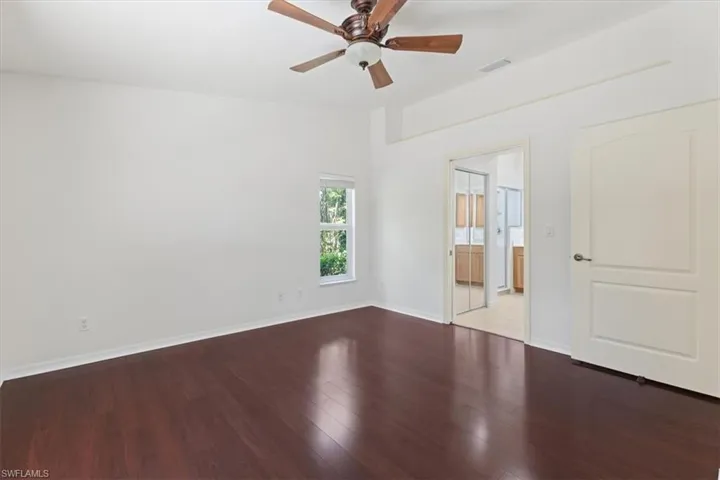 Unfurnished bedroom featuring ceiling fan, hardwood / wood-style flooring, and ensuite bath