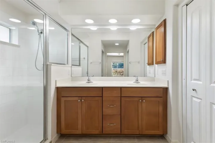Bathroom with a healthy amount of sunlight, vanity, tile patterned flooring, and a shower with shower door