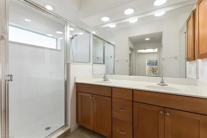 Bathroom featuring tile patterned flooring, vanity, and an enclosed shower