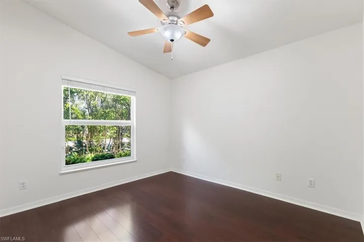 Empty room with ceiling fan, hardwood / wood-style flooring, and lofted ceiling