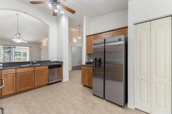 Kitchen with light tile patterned flooring, sink, hanging light fixtures, appliances with stainless steel finishes, and ceiling fan