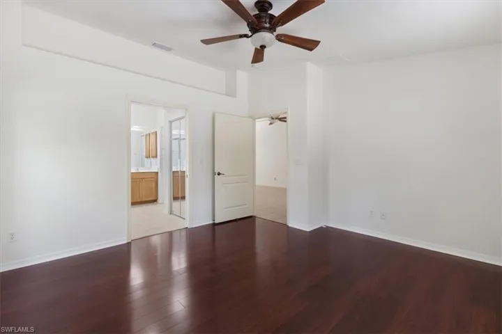 Unfurnished bedroom featuring wood-type flooring, connected bathroom, and ceiling fan