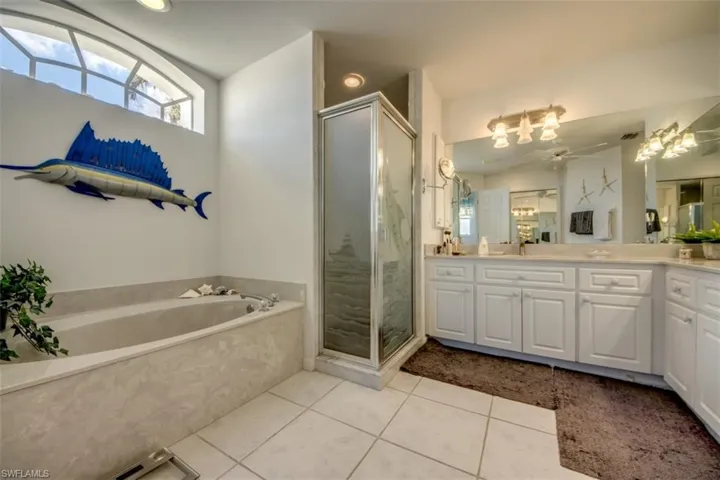 Bathroom with vanity, a shower stall, light tile patterned floors, a garden tub, and ceiling fan