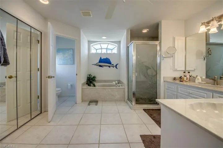 Full bath featuring a bath, a marble finish shower, vanity, light tile patterned floors, and ceiling fan