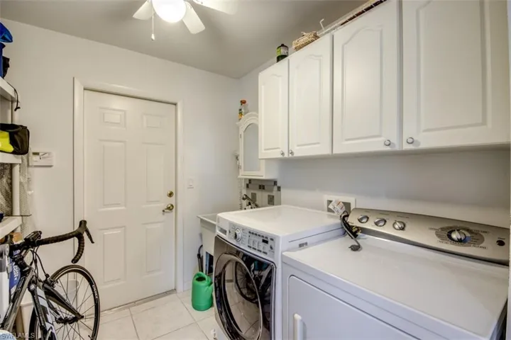 Laundry area with cabinet space, light tile patterned floors, ceiling fan, and separate washer and dryer