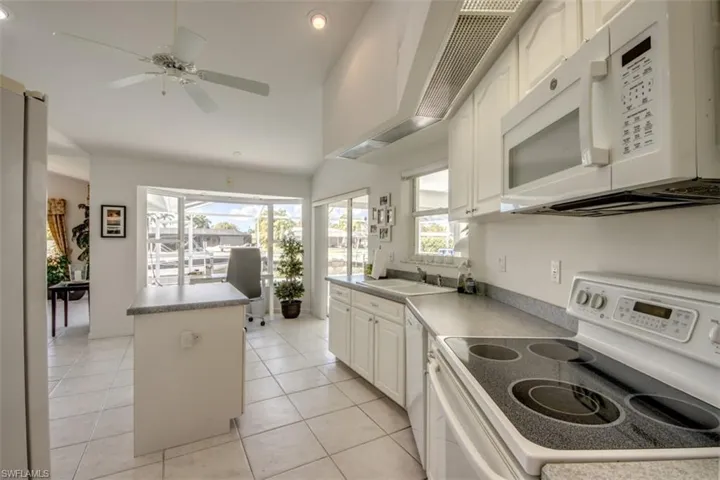 Kitchen featuring white appliances, white cabinetry, recessed lighting, a center island, and light tile patterned floors