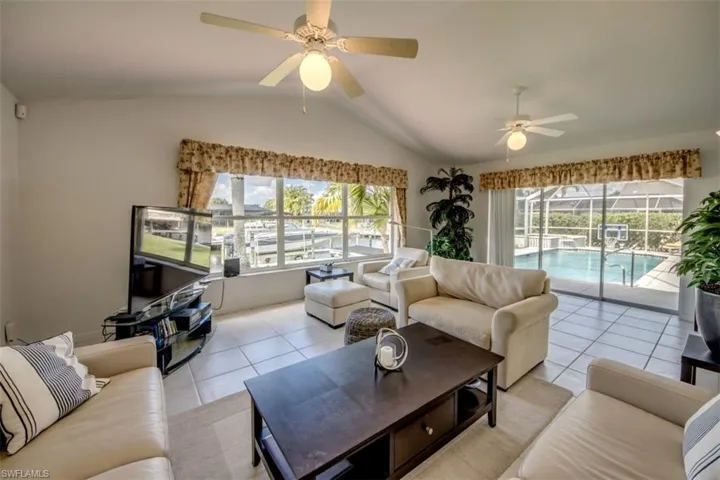 Living area with light tile patterned flooring, a ceiling fan, plenty of natural light, and a sunroom