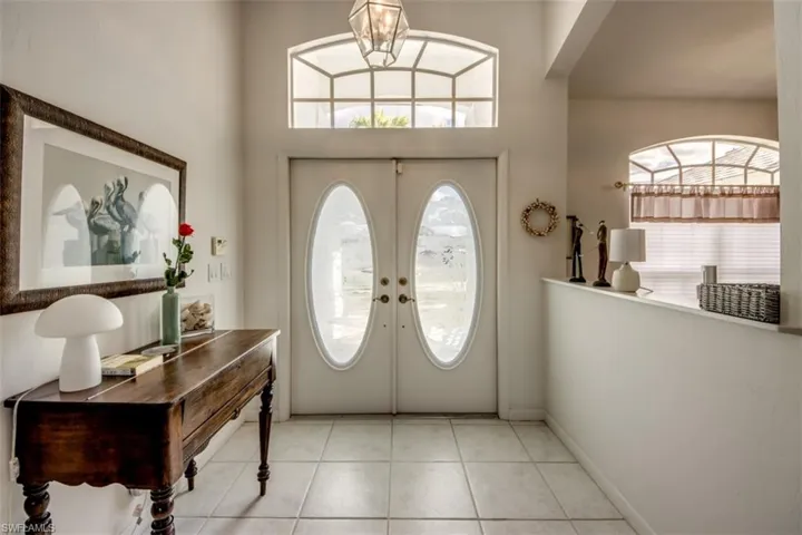 Foyer featuring a chandelier, healthy amount of natural light, light tile patterned floors, and french doors