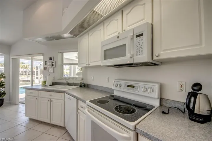 Kitchen featuring white appliances, white cabinets, light tile patterned floors, and light countertops