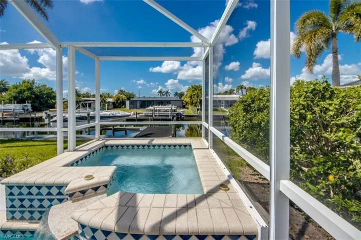 Swimming pool with a water view, boat lift, a dock, and a sunroom
