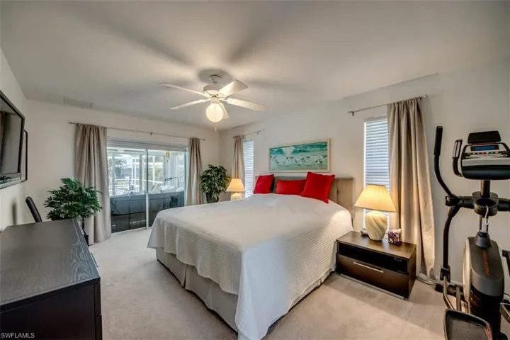 Bedroom with light colored carpet, access to exterior, a ceiling fan, and multiple windows