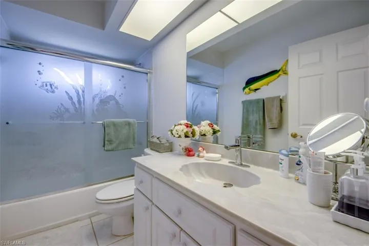 Full bathroom featuring vanity, shower / bath combination with glass door, and light tile patterned flooring
