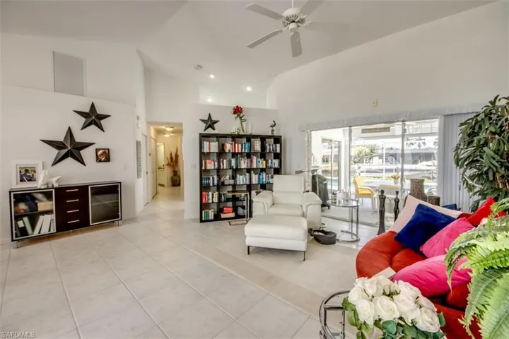 Living area with a ceiling fan, light tile patterned flooring, vaulted ceiling, and recessed lighting
