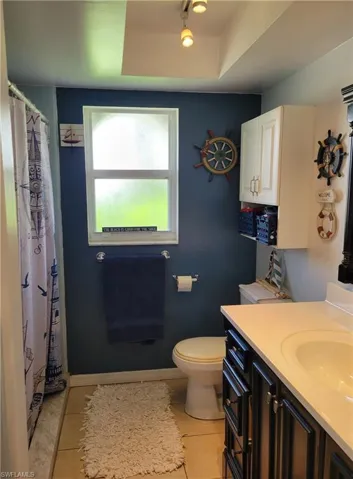Bathroom with tile flooring, vanity, toilet, and a raised ceiling