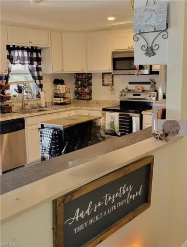 Kitchen with appliances with stainless steel finishes, sink, and white cabinets