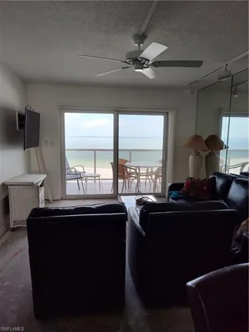 Living room featuring healthy amount of natural light, a textured ceiling, rail lighting, and ceiling fan