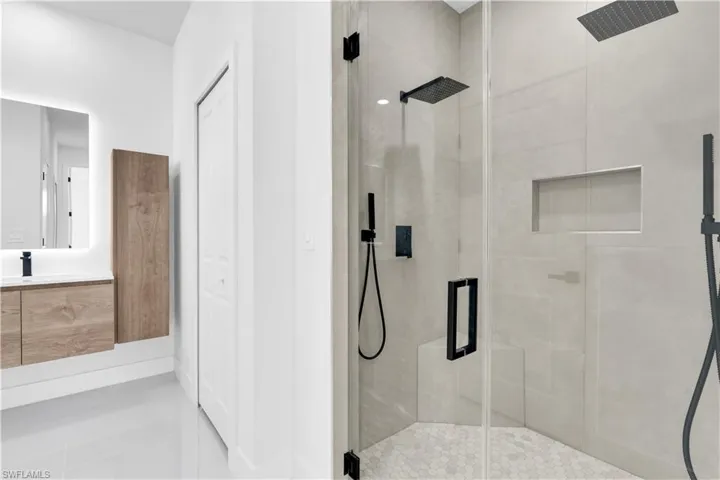 Full bath with tile patterned floors, vanity, and a stall shower