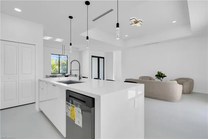 Kitchen with pendant lighting, stainless steel dishwasher, modern cabinets, light countertops, and a sink